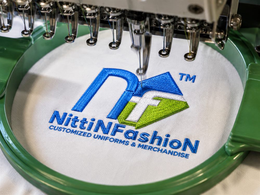 Nittin Fashion logo being machine-embroidered onto white fabric